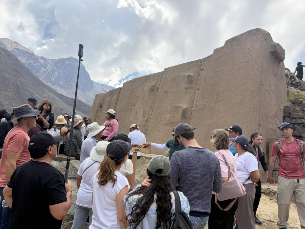 Guide with the group in front of the Wall of the Six Monoliths in Ollantaytambo