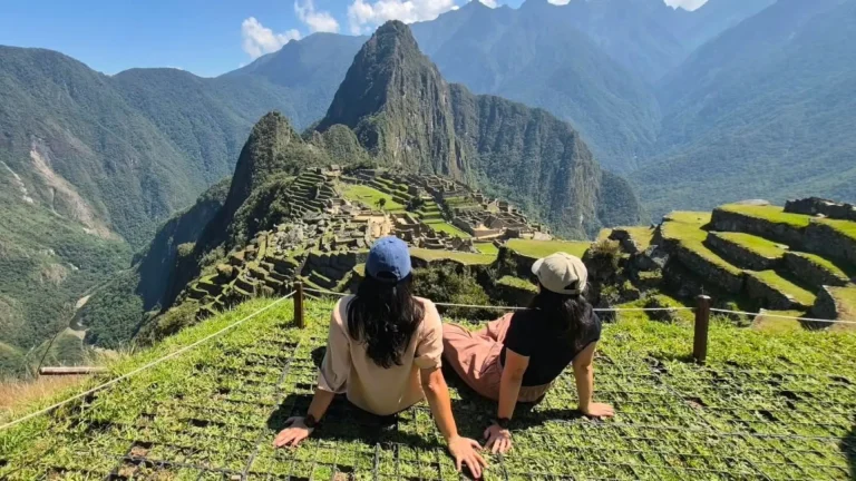 Two travelers looking at the citadel of Machu Picchu from the viewpoint